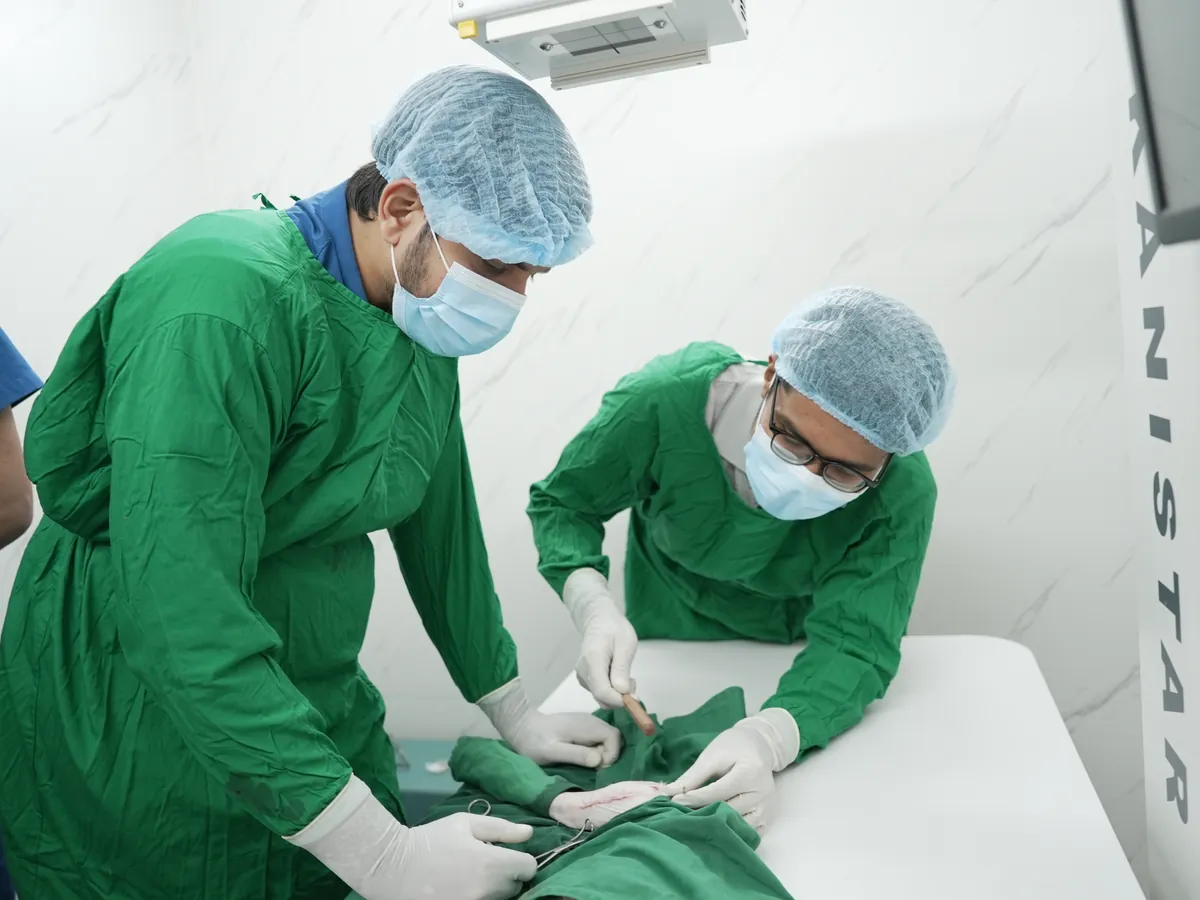 Surgeons in green scrubs operating in the surgical theatre