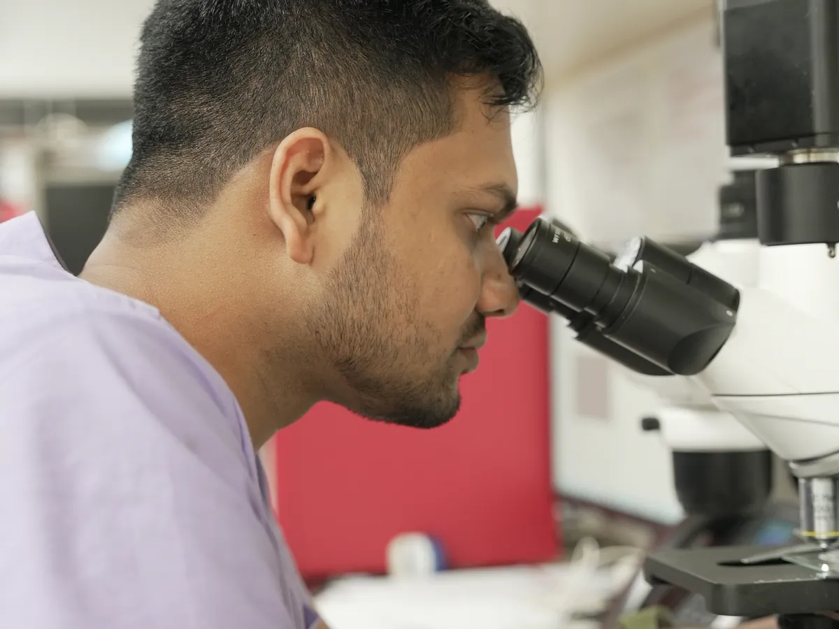 A lab technician reading a slide under the microscope in the in-house laboratory